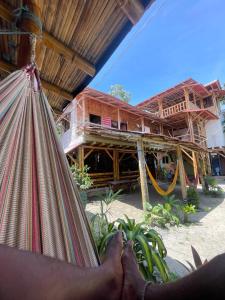 a person laying in a hammock in front of a building at Onda Hostel Mompiche in Mompiche