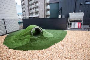 a green grassy area with a building in the background at Shiro in Hakodate