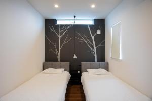 two beds in a room with white sheets at Shiro in Hakodate