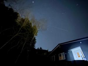 a starry night with a building and a tree at 民宿 浪漫 in Fujikawaguchiko
