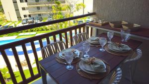 a wooden table with plates and glasses on a balcony at Studio Beira-Mar na Praia dos Carneiros in Tamandaré