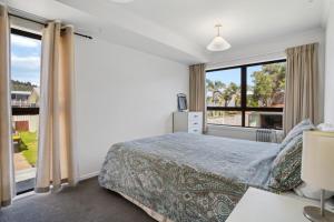a bedroom with a bed and a large window at Tangaroa Beachside Bliss - with Private Pool in Whangamata +17 photos