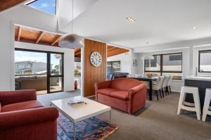 a living room with red chairs and a table at Tangaroa Beachside Bliss - with Private Pool in Whangamata