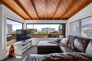 a living room with a couch and a flat screen tv at Tangaroa Beachside Bliss - with Private Pool in Whangamata