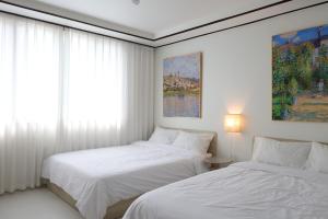 a white bedroom with two beds and a window at Asan Wolang Stay in Asan