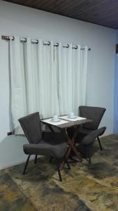 a table and chairs in a room with white curtains at Chalé aconchego sfx in São José dos Campos