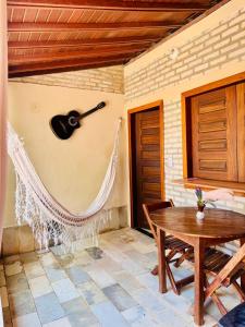 a room with a table and a guitar on the wall at Beach House Suítes Jeri in Jericoacoara