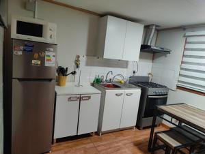 a kitchen with white cabinets and a stainless steel refrigerator at Casa amoblada en Punta arenas in Punta Arenas