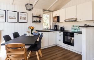 a kitchen with white cabinets and a black table and chairs at Schatzkiste 3 - Dorf 4 in Travemünde