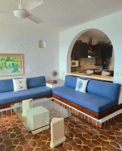 a living room with blue couches and a kitchen at Condumel in Cozumel