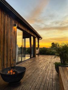 a deck with a fire pit on a house at Chalé romântico com jacuzzi e vista do pôr-do-sol in Harmonia +38 photos