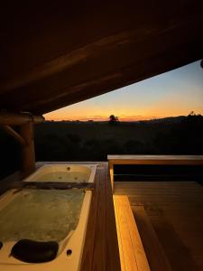 a hot tub on a deck with the sunset in the background at Chalé romântico com jacuzzi e vista do pôr-do-sol in Harmonia