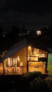 a small house with people standing on a deck at night at Chalé romântico com jacuzzi e vista do pôr-do-sol in Harmonia