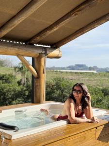 a woman in a hot tub on a deck at Chalé romântico com jacuzzi e vista do pôr-do-sol in Harmonia