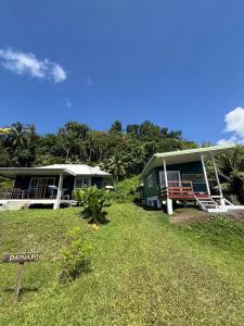 a green house with a sign in front of it at Tuava - Mirimiri Lodge in Ataiti