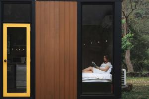 a woman sitting on a bed reading a book at Lanyin Hut in Shui-t'ien
