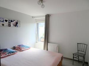 a bedroom with a bed and a chair and a window at Stone House in Bricqueville near Sandy Beach in Bricqueville-sur-Mer
