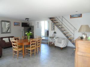 a dining room and living room with a table and a staircase at Stone House in Bricqueville near Sandy Beach in Bricqueville-sur-Mer