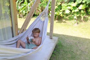 a boy sitting in a hammock reading a book at SHINMINKA Villa UTTABARU in Amami