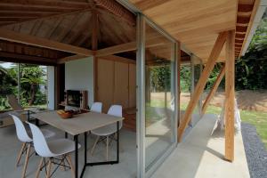 a glass house with a table and white chairs at SHINMINKA Villa UTTABARU in Amami