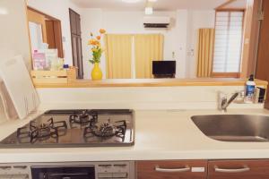 a kitchen with a stove top oven next to a sink at 民泊八のや in Hachioji