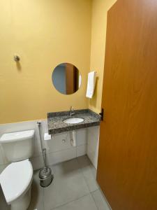 a bathroom with a toilet and a sink with a mirror at Hotel Grajaú in Arcos