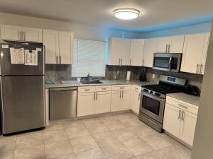 a kitchen with white cabinets and stainless steel appliances at Bright & Comfortable Home in the Heart of It All in Central Islip