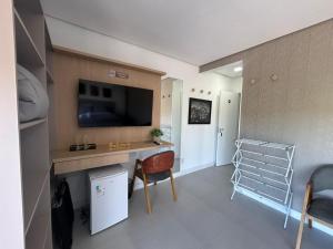 a living room with a desk and a tv on a wall at Esplendor Residence Seu Paraíso em Atlântida com Piscina in Xangri-lá
