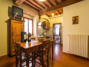 a kitchen with a wooden table with chairs and a television at Mansion with Pool and play area in Pian di Scò