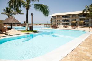 a large swimming pool at a resort with palm trees at Pé na areia - verdadeiro paraíso em Muro Alto in Porto De Galinhas