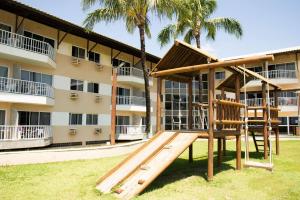 a playground in front of a building with palm trees at Pé na areia - verdadeiro paraíso em Muro Alto in Porto De Galinhas