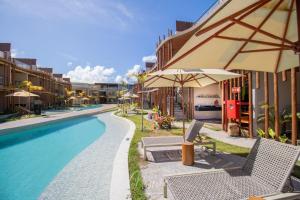 a pool with chairs and umbrellas next to a building at Naay - Sun 008 in Pôrto de Pedras
