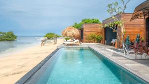a swimming pool next to a beach with a house at Sea Sun Beach Villa in Nusa Lembongan