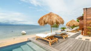 a deck with chairs and an umbrella and the ocean at Sea Sun Beach Villa in Nusa Lembongan