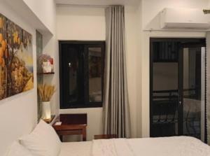a bedroom with a bed and a window and a desk at ICHI Home Kim Long in Hue