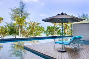 a chair and an umbrella next to a swimming pool at Angsana Teluk Bahang, Penang in Batu Ferringhi