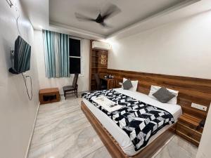 a bedroom with a bed and a chair and a television at Landlord Premier in Rohtak +62 photos