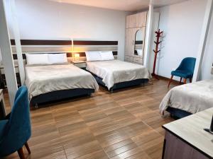 a hotel room with two beds and a table and chairs at Cusco Center Apartment in Cusco