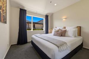 a bedroom with a large bed with a large window at Daffodil Apartments in Christchurch