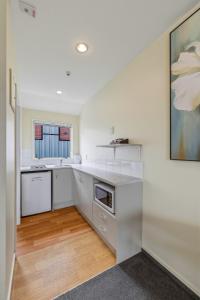 a kitchen with white appliances and a painting on the wall at Daffodil Apartments in Christchurch +10 photos