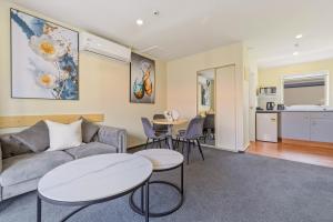 a living room with a couch and two tables at Daffodil Apartments in Christchurch