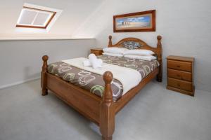 a bedroom with a wooden bed with white pillows at Parkwood 6 - 2BR Split Lvl Apartment l Spa Bath l BBQ l Central Location in Jindabyne