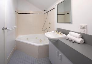a white bathroom with a sink and a bath tub at Parkwood 6 - 2BR Split Lvl Apartment l Spa Bath l BBQ l Central Location in Jindabyne +9 photos