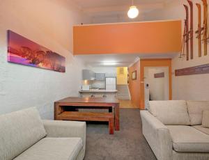 a living room with two couches and a table at Parkwood 6 - 2BR Split Lvl Apartment l Spa Bath l BBQ l Central Location in Jindabyne