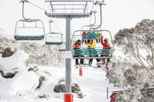 a group of people riding a ski lift in the snow at Parkwood 6 - 2BR Split Lvl Apartment l Spa Bath l BBQ l Central Location in Jindabyne