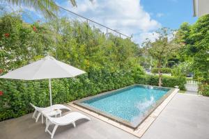 a swimming pool with an umbrella and a chair and a table and an umbrella at Premier Villa Resort Danang in Danang