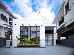a white facade of a building with plants at SMIRE STAY Ishigaki in Ishigaki Island