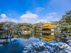 a chinese building on a lake in the snow at Urban Hotel Kyoto in Kyoto