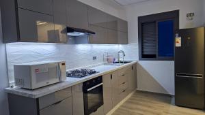 a kitchen with a microwave and a stove top oven at Central Premium Holiday Homes - Marché, Corniche & Océan à pied in Larache