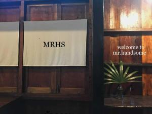 a sign on a wooden wall with a welcome to mris sign at mr handsome phayao in Ban Mae Ka Hua Thung